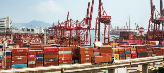 porto commerciale con gru rosse e pile di container multicolore